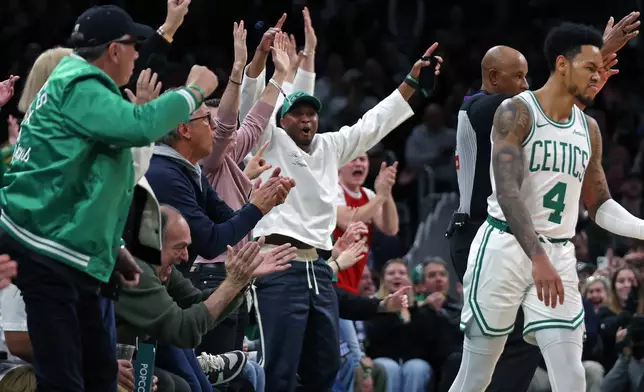 Fans erupt at left after Boston Celtics guard Anfernee Simons (4) hit a three point shot as the buzzer sounded for the end of the first quarter that tied the game. The Milwaukee Bucks met the Boston Celtics in an NBA basketball game, Sunday, Feb. 1, 2026, in Boston. (AP Photo/Jim Davis)