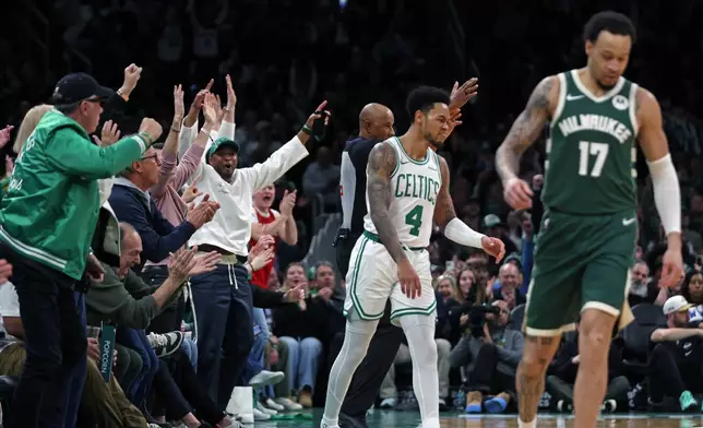 Fans, left, react after Boston Celtics guard Anfernee Simons (4) hit a 3-point basket as the buzzer sounded for the end of the first quarter of an NBA basketball game against the Milwaukee Bucks, Sunday, Feb 1, 2026, in Boston. (AP Photo/Jim Davis)