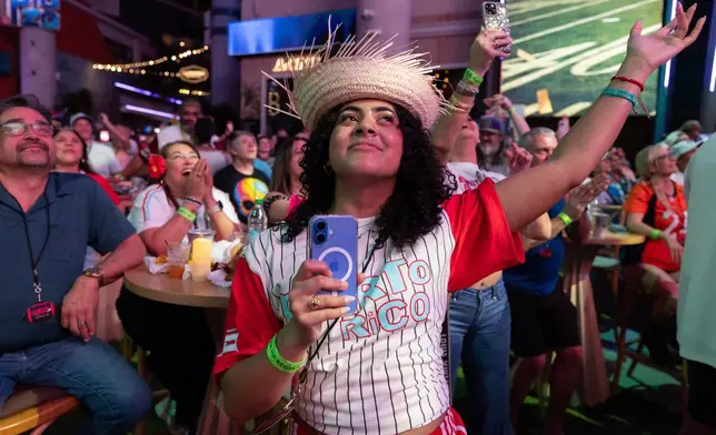 Fans in San Juan, Puerto Rico, watch Bad Bunny's performance on television during the halftime show of the NFL Super Bowl 60 football game Sunday, Feb. 8, 2026. (AP Photo/Alejandro Granadillo)