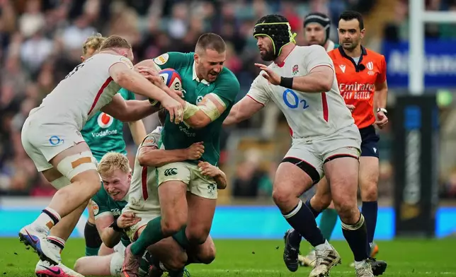 Ireland's Stuart McCloskey, center, is tackled from behind during the Six Nations rugby union match between England and Ireland in London, England, Saturday, Feb. 21, 2026. (AP Photo/Alastair Grant)
