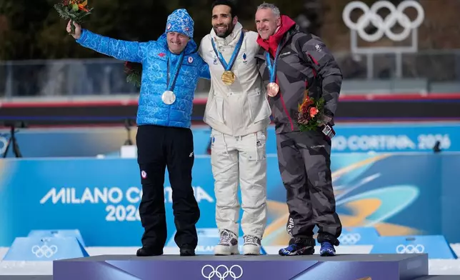 Martin Fourcade, of France, center, poses with the gold medal for the men's 15-kilometer mass start biathlon race from the 2010 Vancouver Winter Olympics with silver medalist Pavol Hurajt, of Slovakia, left, and bronze medalist Christoph Sumann, of Austria, during a reallocation medals ceremony at the 2026 Winter Olympics in Anterselva, Italy, Sunday, Feb. 15, 2026. (AP Photo/Mosa'ab Elshamy)