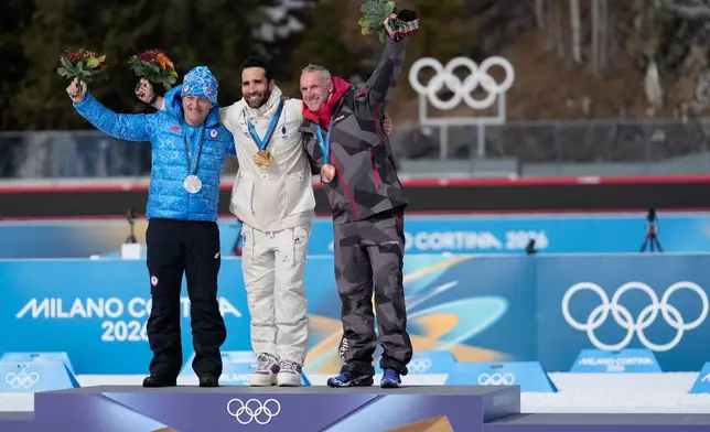 Martin Fourcade, of France, center, poses with the gold medal for the men's 15-kilometer mass start biathlon race from the 2010 Vancouver Winter Olympics with Pavol Hurajt, of Slovakia, left, and Christoph Sumann, of Austria, during a reallocation medals ceremony at the 2026 Winter Olympics in Anterselva, Italy, Sunday, Feb. 15, 2026. (AP Photo/Mosa'ab Elshamy)