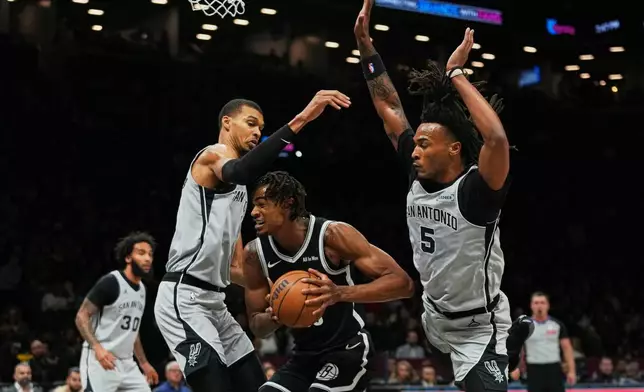 San Antonio Spurs' Victor Wembanyama, left, and Stephon Castle, right, defends Brooklyn Nets' Nic Claxton during the first half of an NBA basketball game Thursday, Feb. 26, 2026, in New York. (AP Photo/Frank Franklin II)