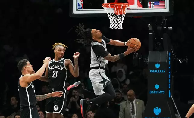 San Antonio Spurs' Stephon Castle, right, drives past Brooklyn Nets' Noah Clowney, center, and Michael Porter Jr. during the first half of an NBA basketball game Thursday, Feb. 26, 2026, in New York. (AP Photo/Frank Franklin II)