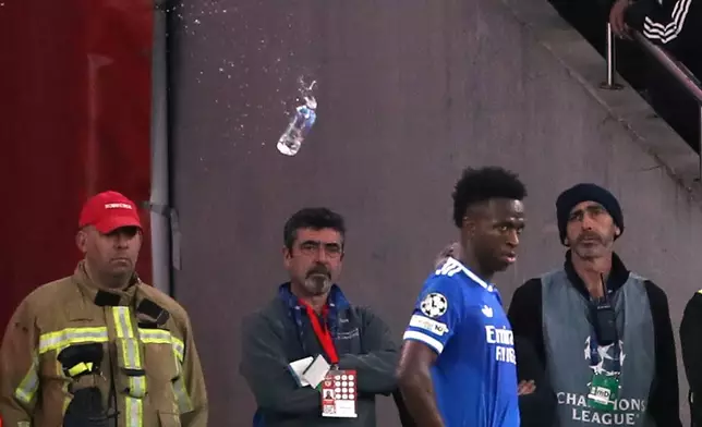 A plastic bottle filled with water is thrown from the stands toward Real Madrid's Vinícius Júnior during a Champions League playoff soccer match between Benfica and Real Madrid in Lisbon, Portugal, Tuesday, Feb. 17, 2026. (AP Photo/Pedro Rocha)