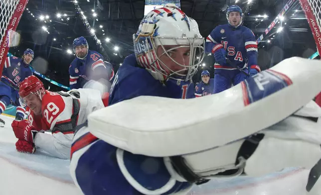 United States' goalkeeper Jeremy Swayman dives to makes a save as Denmark's Nick Olesen scores his side's opening goal during a preliminary round game of men's ice hockey between the United States and Denmark at the 2026 Winter Olympics, in Milan, Italy, Saturday, Feb. 14, 2026. (Bruce Bennett/Pool Photo via AP)