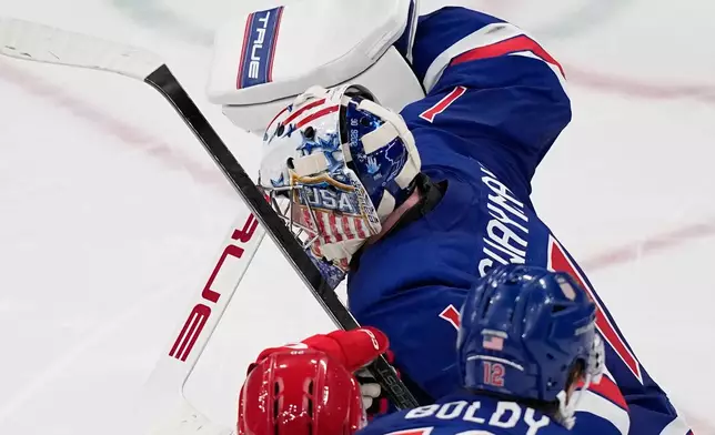 United States' goalkeeper Jeremy Swayman, right, makes a save against Denmark's Lars Eller, center, during a preliminary round match of men's ice hockey between United States and Denmark at the 2026 Winter Olympics, in Milan, Italy, Saturday, Feb. 14, 2026. (AP Photo/Petr David Josek)