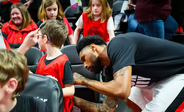 Portland Trail Blazers guard Blake Wesley, right, gives autographs during warmups before an NBA basketball game against the Memphis Grizzlies, Friday, Feb. 6, 2026, in Portland, Ore. (AP Photo/Molly J. Smith)
