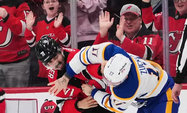 New Jersey Devils' Jonas Siegenthaler (71) punches Buffalo Sabres' Jason Zucker (17) during the second period of an NHL hockey game Wednesday, Feb. 25, 2026, in Newark, N.J. (AP Photo/Frank Franklin II)