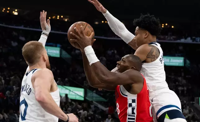 Los Angeles Clippers guard Kris Dunn, center, goes up for a basket as Minnesota Timberwolves guards Terrence Shannon Jr., right, and Donte DiVincenzo, left, defend against him during the first half of an NBA basketball game Thursday, Feb. 26, 2026, in Inglewood, Calif. (AP Photo/Kyusung Gong)