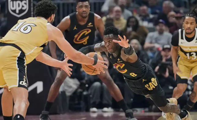 Washington Wizards forward Anthony Gill (16) and Cleveland Cavaliers' Dennis Schroder (8) reach for the ball in the first half of an NBA basketball game in Cleveland, Wednesday, Feb. 11, 2026. (AP Photo/Sue Ogrocki)