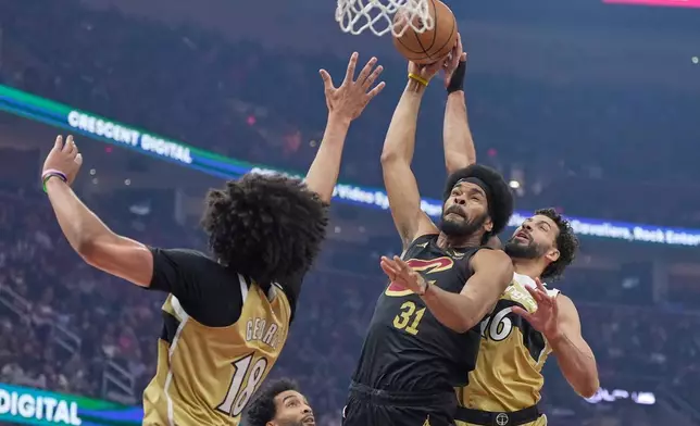 Cleveland Cavaliers center Jarrett Allen (31) shoots between Washington Wizards forward Kyshawn George (18) and forward Anthony Gill (16) in the first half of an NBA basketball game in Cleveland, Wednesday, Feb. 11, 2026. (AP Photo/Sue Ogrocki)