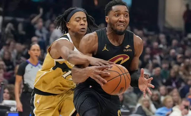Washington Wizards' Skal Labissiere, left, knocks the ball away from Cleveland Cavaliers guard Donovan Mitchell, right, in the first half of an NBA basketball game in Cleveland, Wednesday, Feb. 11, 2026. (AP Photo/Sue Ogrocki)