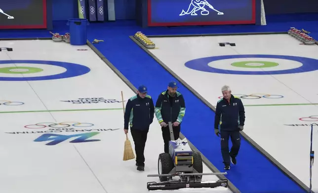 Staff members level the ice before the bronze medal curling mixed doubles match at the 2026 Winter Olympics, in Cortina d'Ampezzo, Italy, Tuesday, Feb. 10, 2026. (AP Photo/Misper Apawu)