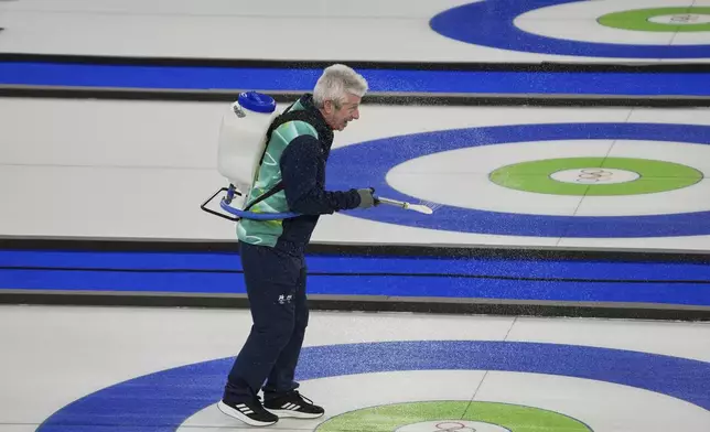 A staff member sprays water on the ice before the bronze medal curling mixed doubles match at the 2026 Winter Olympics, in Cortina d'Ampezzo, Italy, Tuesday, Feb. 10, 2026. (AP Photo/Misper Apawu)