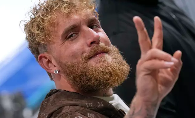 Jake Paul of the U.S. flashes a V-sign as he arrives to support his fiancé Jutta Leerdam of the Netherlands competing in the women's 1,000 meters speedskating race at the 2026 Winter Olympics, in Milan, Italy, Monday, Feb. 9, 2026. (AP Photo/Luca Bruno)