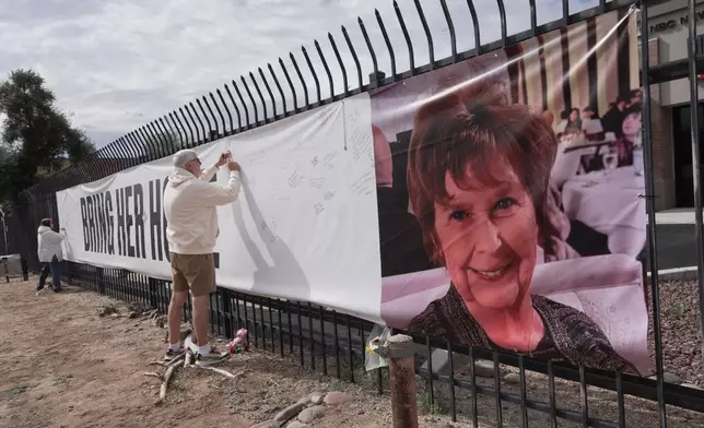 Jeff Robb, a Seattle resident wintering in Tucson, signs a banner supporting Nancy Guthrie in Tucson Ariz., on Friday, Feb. 13, 2026. (AP Photo/Ty ONeil)
