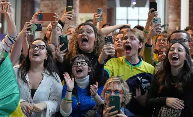 Supporters of Brazil's Lucas Pinheiro Braathen react at the Brazil House as he starts his second run in the men's giant slalom at the 2026 Winter Olympics, in Milan, Italy, Saturday, Feb. 14, 2026. (AP Photo/Antonio Calanni)