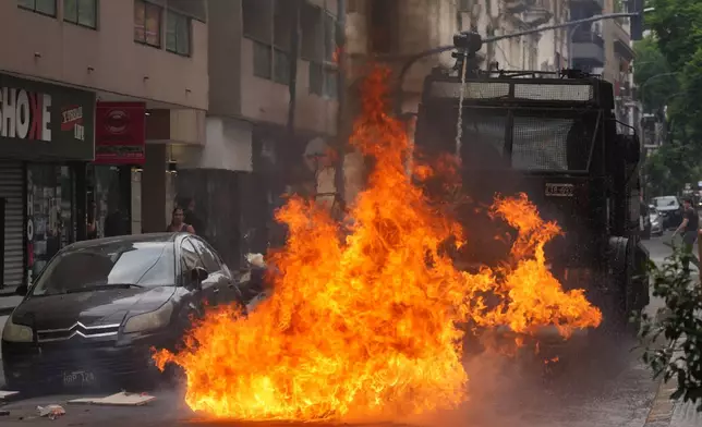A police water cannon sprays a fire sparked by a Molotov cocktail during clashes at a march by trade unions and opposition groups against a labor reform bill proposed by President Javier Milei's government in Buenos Aires, Argentina, Wednesday, Feb. 11, 2026. (AP Photo/Gustavo Garello)