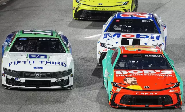 Denny Hamlin (11) passes Chris Buescher (17) in Turn 1 during NASCAR's The Clash preseason auto race at Bowman Gray Stadium, Wednesday, Feb. 4, 2026, in Winston-Salem, N.C. (AP Photo/Matt Kelley)