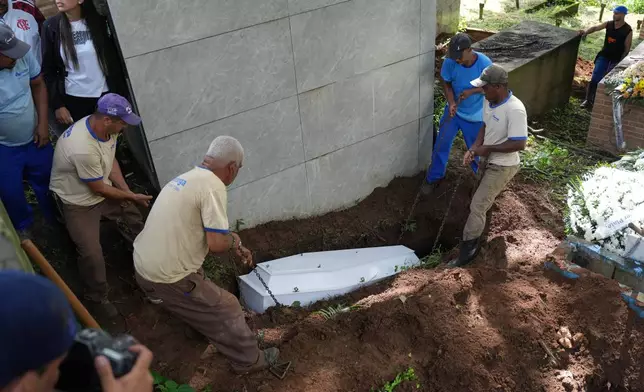Cemetery workers lower the coffin of the remains of 11-year-old Bernardo Lopes, a victim of heavy rains and flooding in Juiz de Fora, Minas Gerais state, Brazil Wednesday, Feb. 25, 2026. (AP Photo/Silvia Izquierdo)