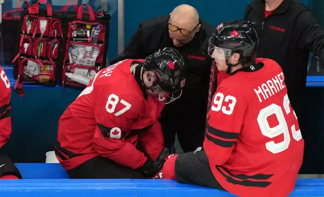 Canada's Sidney Crosby (87) is attended to after being injured during the second period of a men's ice hockey quarterfinal game between Canada and Czechia at the 2026 Winter Olympics, in Milan, Italy, Wednesday, Feb. 18, 2026. (AP Photo/Hassan Ammar)
