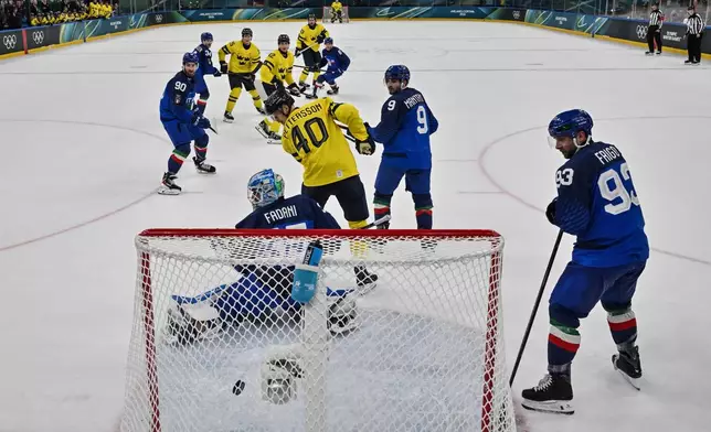Sweden's Mika Zibanejad (rear C) shoots and scores his team fourth goal during the men's preliminary round Group B Ice Hockey match between Sweden and Italy at the 2026 Winter Olympics, in Milan, Italy, Wednesday, Feb. 11, 2026. (Alexander Nemenov/Pool Photo via AP)