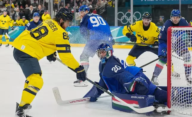 Italy's goalkeeper Damian Clara (20) makes a save against Sweden's William Nylander (88) during a preliminary round match of men's ice hockey between Italy and Sweden at the 2026 Winter Olympics, in Milan, Italy, Wednesday, Feb. 11, 2026. (AP Photo/Hassan Ammar)