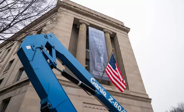 A banner showing President Donald Trump is hung from the Department of Justice, Thursday, Feb. 19, 2026, in Washington. (AP Photo/Allison Robbert)