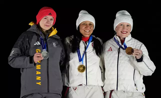 From left, Germany's silver medalist Laura Nolte, United States' gold medalist Elana Meyers Taylor and United States' bronze medalist Kaillie Armbruster Humphries pose for photos on the podium of a women's monobob competition at the 2026 Winter Olympics, in Cortina d'Ampezzo, Italy, Monday, Feb. 16, 2026. (AP Photo/Alessandra Tarantino)