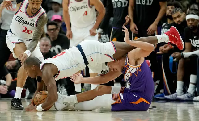 Los Angeles Clippers guard Kris Dunn, left, battles with Phoenix Suns guard Grayson Allen, right, for a loose ball as Clippers forward John Collins (20) looks for the ball during the first half of an NBA basketball game Sunday, Feb. 1, 2026, in Phoenix. (AP Photo/Ross D. Franklin)