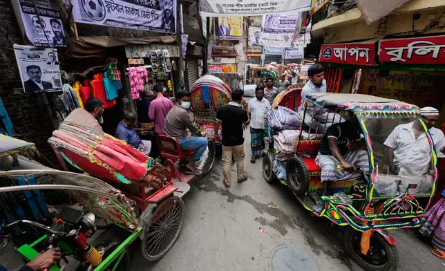 Commuters travel on rickshaws in a market on the eve of national election in Dhaka, Bangladesh, Tuesday, Feb. 10, 2026. (AP Photo/Anupam Nath)