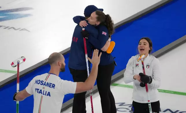 Italy's Amos Mosaner and Stefania Constantini celebrate as Britain's Bruce Mouat and Jennifer Dodds hug at the end of the bronze medal mixed doubles curling match, at the 2026 Winter Olympics, in Cortina D'Ampezzo, Italy, Tuesday, Feb. 10, 2026. (AP Photo/Misper Apawu)