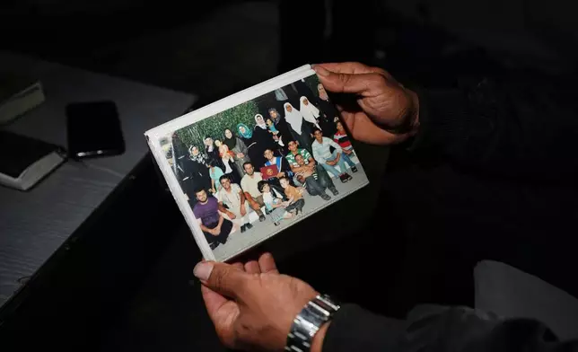 Saddam al-Yazji holds a photo of his family in Gaza City Tuesday, Feb. 24, 2026. (AP Photo/Jehad Alshrafi)