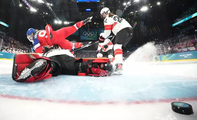 Czechia's Kristyna Kaltounkova, left, falls over Switzerland's Saskia Maurer while scoring her sides first goal during a preliminary round match of women's ice hockey between Switzerland and Czechia at the 2026 Winter Olympics, in Milan, Italy, Friday, Feb. 6, 2026. (David W Cherny/Pool Photo via AP)