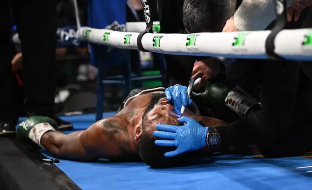 Trainers check on Joe George Jr. after he collapsed in his corner after the first round of his light heavyweight boxing match against Atif Oberlton, Sunday, Feb. 22, 2026, in Detroit. (AP Photo/Lon Horwedel)