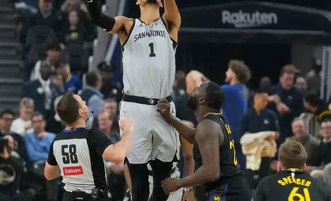 San Antonio Spurs center Victor Wembanyama (1) reaches for the opening tip-off over Golden State Warriors forward Draymond Green during the first half of an NBA basketball game in San Francisco, Wednesday, Feb. 11, 2026. (AP Photo/Jeff Chiu)