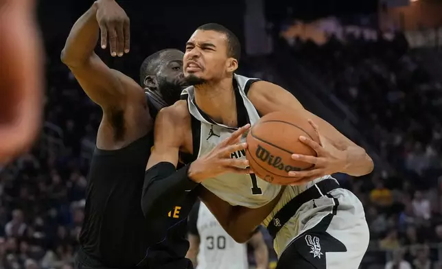 San Antonio Spurs center Victor Wembanyama, right, drives to the basket against Golden State Warriors forward Draymond Green during the first half of an NBA basketball game in San Francisco, Wednesday, Feb. 11, 2026. (AP Photo/Jeff Chiu)