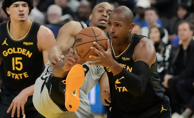 Golden State Warriors center Al Horford, right, grabs a rebound against San Antonio Spurs guard Keldon Johnson during the first half of an NBA basketball game in San Francisco, Wednesday, Feb. 11, 2026. (AP Photo/Jeff Chiu)