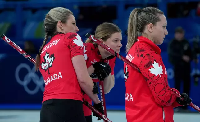 Canada's Emma Miskew, left, Rachel Homan, right, and Sarah Wilkes study the situation during a women's curling semifinal match against Sweden, at the 2026 Winter Olympics, in Cortina d'Ampezzo, Italy, Friday, Feb. 20, 2026. (AP Photo/Misper Apawu)