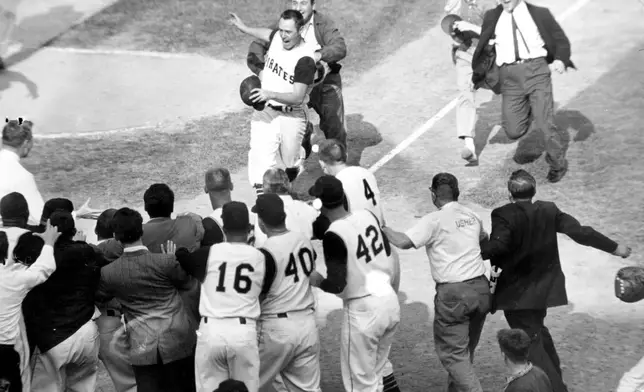 FILE - Baseball fans rush onto the field toward Pittsburgh Pirates second baseman Bill Mazeroski as he comes home after hitting a ninth inning home run to win Game 7 of baseball's World Series agains the New York Yankees in Pittsburgh, Pa., on Oct. 13, 1960. (AP Photo/Harry Harris, File)