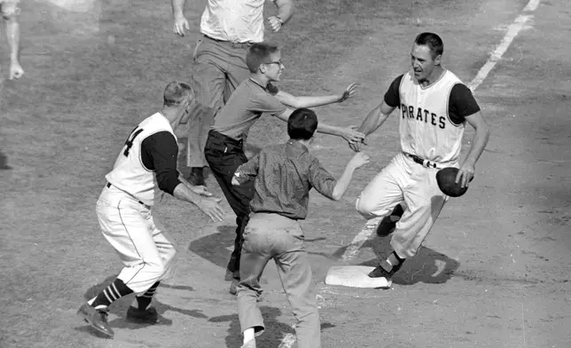 FILE - In this Oct. 13, 1960 file photo, jubilant Pittsburgh Pirates fans rush onto the field to congratulate second baseman Bill Mazeroski as he rounds third base after hitting a ninth inning home run to win Game 7 of baseball's World Series against the New York Yankees in Pittsburgh, Pa., on Oct. 13, 1960. (AP Photo/Harry Harris, File)