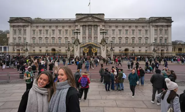 Visitors pose for pictures in front of Buckingham Palace in London, Thursday, Feb. 19, 2026 after Andrew Mountbatten-Windsor has been arrested by British police on suspicion of misconduct in public office. (AP Photo/Kin Cheung)