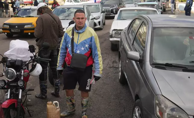 A man wearing a jacket in the colors of Venezuela's flag lines up to purchase fuel at a gas station in Havana, Cuba, Friday, Feb. 6, 2026. (AP Photo/Ramon Espinosa)