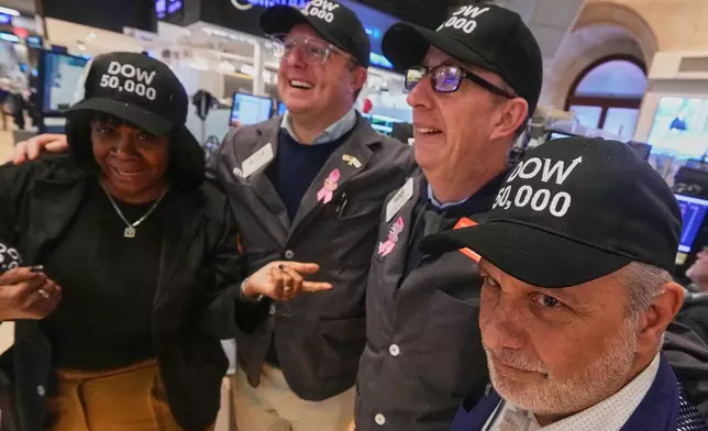 Trader Joel Lucchese, right, and colleagues wear "DOW 50,000" caps on the floor of the New York Stock Exchange as the Dow Jones industrial average intra-day number topped the 50,000 level for the first time, Friday, Feb. 6, 2026. (AP Photo/Richard Drew)