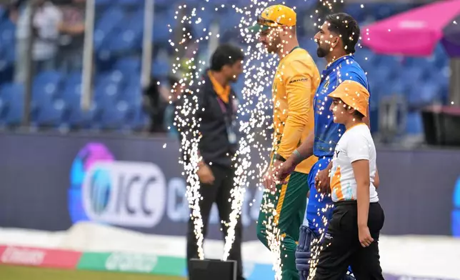 South Africa's David Miller, left, and United Arab Emirates' captain Muhammad Waseem walk into the field before the start of their T20 World Cup cricket match between South Africa and United Arab Emirates in New Delhi, India, Wednesday, Feb. 18, 2026. (AP Photo/Manish Swarup)