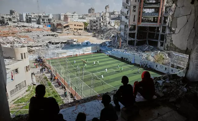 Palestinian children watch amputee soccer players training on a newly constructed field surrounded by buildings destroyed in Israeli army bombardments during the Israel-Hamas war, in Gaza City, Wednesday, Feb. 11, 2026. (AP Photo/Jehad Alshrafi)