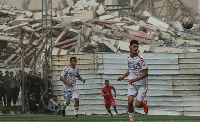 A Palestinian player of Gaza Sports Club, right, controls the ball during a soccer match with Al-Ahly Club at a newly constructed field surrounded by buildings destroyed in Israeli ground and air operations, in Gaza City, Saturday, Feb. 14, 2026. (AP Photo/Jehad Alshrafi)