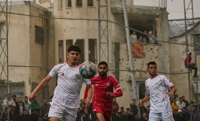 A Palestinian player of Gaza Sports Club, left, controls the ball during a soccer match with Al-Ahly Club at a newly constructed field surrounded by buildings destroyed in Israeli ground and air operations, in Gaza City, Saturday, Feb. 14, 2026. (AP Photo/Jehad Alshrafi)