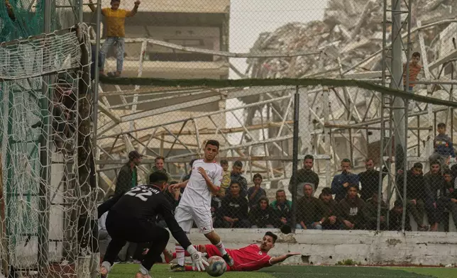A Palestinian goalkeeper of Al-Ahly Club saves a shot by Gaza Sports Club's player, center, during a soccer match at a newly constructed field surrounded by buildings destroyed in Israeli ground and air operations, in Gaza City, Saturday, Feb. 14, 2026. (AP Photo/Jehad Alshrafi)